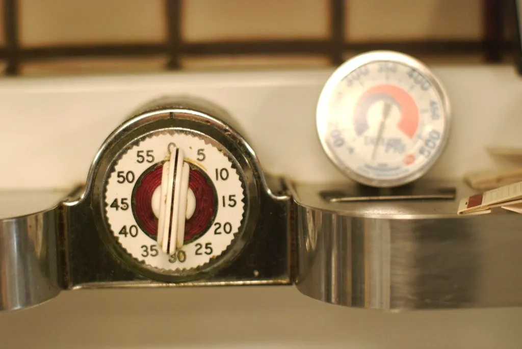 A red kitchen timer sitting on a wooden countertop