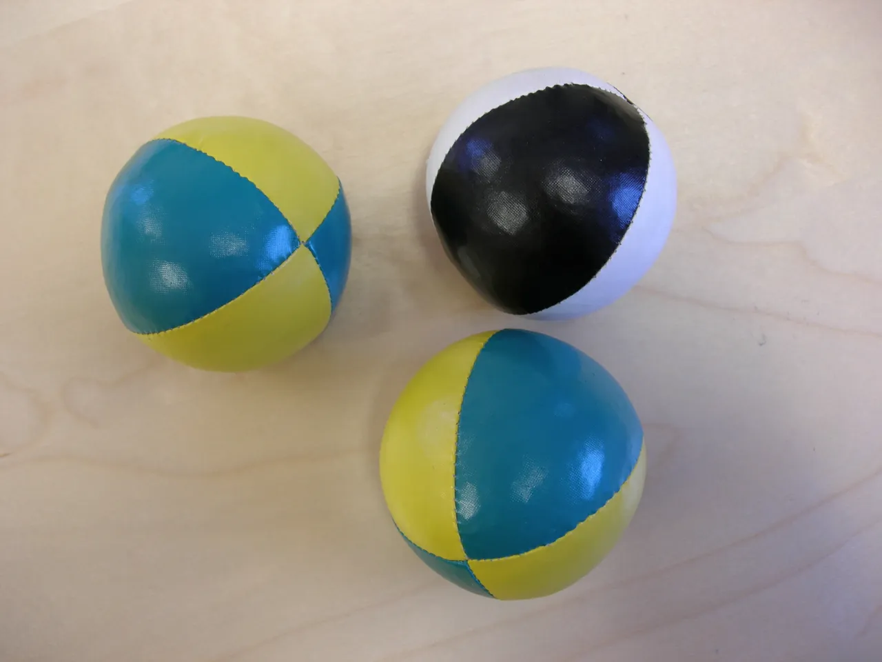 Three juggling balls resting on a wooden table