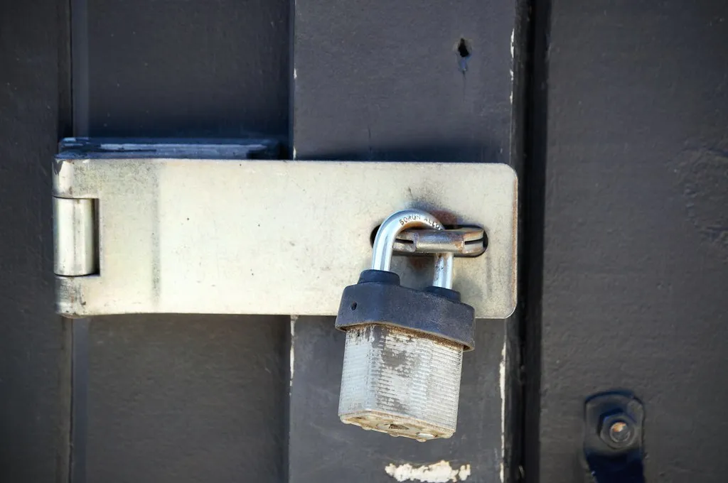 A brass padlock resting closed against a metal surface